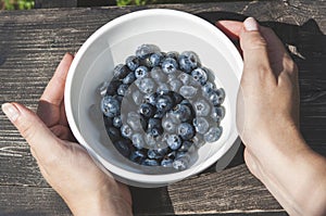 Close up of a woman holding a bowl of blueberries