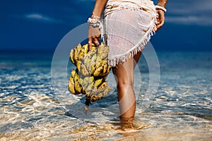 Close up of woman holding bunch of banans on the beach