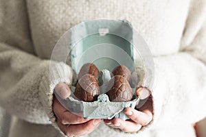 Close up of woman holding carton egg box with easter chocolate eggs