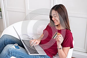 Close up woman holding credit card and use laptop shopping online on sofa in house.digital payment marketing technology concept.