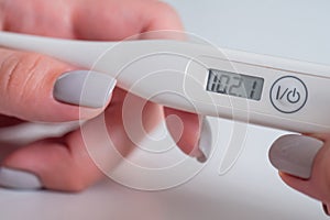 Close up: woman holding digital medical thermometer with high temperature