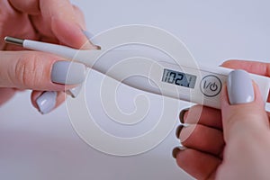 Close up: woman holding digital medical thermometer with high temperature