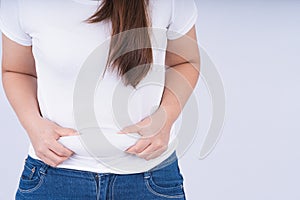 Close-up woman holding excessive belly fat, overweight abdomen on white background. Weight loss, diet lifestyle, healthy concept