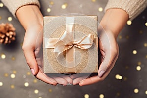 Close up of a woman holding a luxury gift box present wrapped with gold ribbon and golden glitter