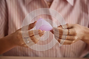 Close Up of Woman Holding Menstrual Cup Against Pink Shirt