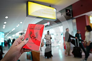 Close up of woman holding a passport of Singapore at the Airport