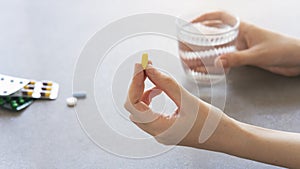 Close up woman holding pill in hand with water. Female going to take tablet from headache, painkiller, medication drinking clear w