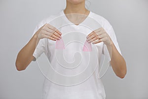 Close up of woman holding pink menstrual cups of different size in her hands on white background. Gynecology concept