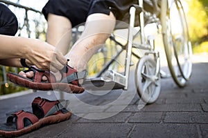 Close up of woman holding a shoes in her hand, putting a shoes for elderly or disabled in a wheelchair, care and good relations in