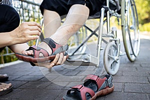 Close up of woman holding a shoes in her hand, wearing a shoes for disabled senior in a wheelchair, care,service and assistance,