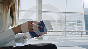 Close-up, Woman holds air tickets and passports in her hands against the backdrop of empty check-in counters at the