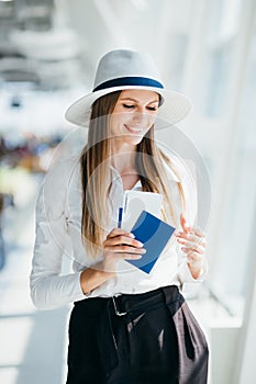 Close-up, Woman holds air tickets and passports in her hands against the backdrop of empty check-in counters at the