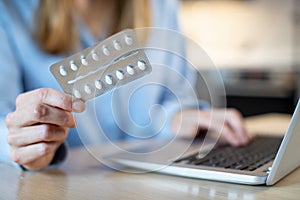 Close Up Of Woman At Home Looking Up Information About Medication Online Using Laptop