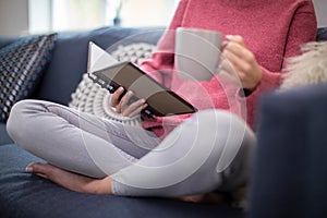 Close Up Of Woman With Hot Drink Relaxing On Sofa At Home Reading Journal