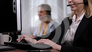 Close-up of a woman hotline operator working at a computer in the office.
