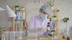 Close up woman laboratory technician conducts research using a microscope