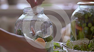 Close-up of a Woman Laying in a Glass Bank with Cucumbers Sliced Carrots and White Pepper for Cooking