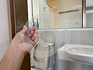 close up woman left hand twist vintage door knob to enter bathroom