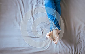 Close up of woman legs with blue jeans,Feet and stretch lazily on bed