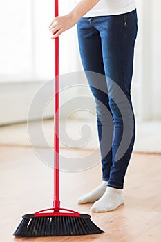 Close up of woman legs with broom sweeping floor