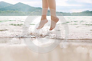 Close up of woman legs jumping on the wave at the beach