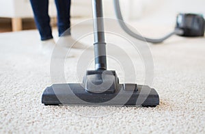 Close up of woman legs with vacuum cleaner at home