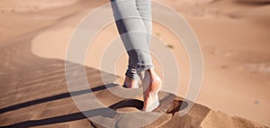 close up on woman legs walking on sand dune