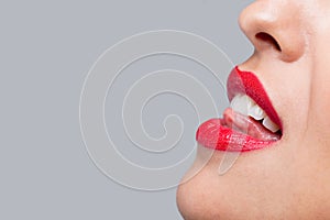 Close up woman licking her red teeth.