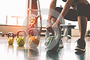 Close up of woman lifting kettlebell like dumbbells in fitness sport club gym training center with sport equipment near window