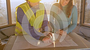 CLOSE UP: Woman listens to architect explaining the floor plans at sunrise.