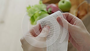 Close-up woman looking a check from a supermarket. Expense tracking and budgeting