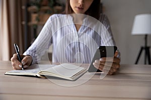 Close up of woman make notes using smartphone