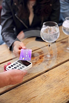 Close Up Of Woman Making Contactless Payment Using Card At Outdoor Bar