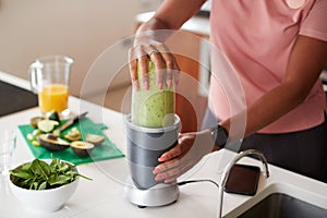 Close Up Of Woman Making Healthy Juice Drink With Fresh Ingredients In Electric Juicer After Exercise