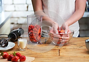 Close up of woman making strawberry smoothie. Healthy eating, cooking and summer refreshment concepts