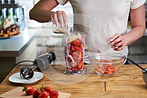 Close up of woman making strawberry smoothie. Healthy eating, cooking and summer refreshment concepts