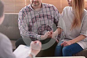 Close-up of woman and man holding hands on a couch during a psychotherapy session. Couples therapy concept