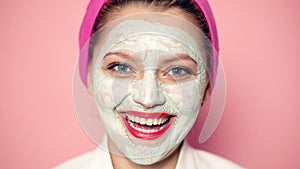 Close up of woman with mask on her face on pink background. Model with facial mask. Face care, facial concept. Funny