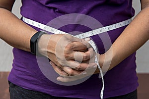 Close up of a woman measuring her waist with measuring tape