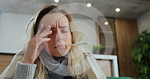 Close up of woman measuring temperature with electronic thermometer at home. Sick woman measuring temperature at home