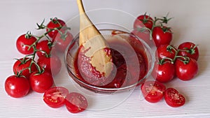 Close-up of a woman mixing tomato paste in a bowl with a wooden spoon.