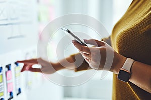 Woman with mobile phone planning website on whiteboard