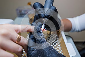 Close-up of a woman in a nail salon getting a manicure in a beauty salon from a beautician who uses an electric nail polish