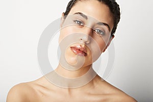 Close-up woman naked shoulders clean skin and nude make up posing over pink wall in front of a camera. Space for text. photo