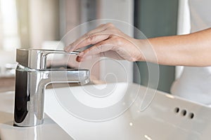 Close up Woman open chrome faucet washbasin to washing hands rubbing with soap for corona virus at water tap. Faucet and water