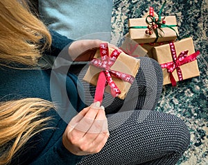 Close up on woman opening christmas present box with more gifts on background