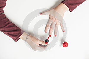 Close-up of a woman painting her nails with red lacquer