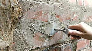 Close up of woman pointing brick wall with mortar.
