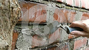 Close up of woman pointing brick wall with mortar.