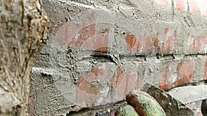 Close up of woman pointing brick wall with mortar.